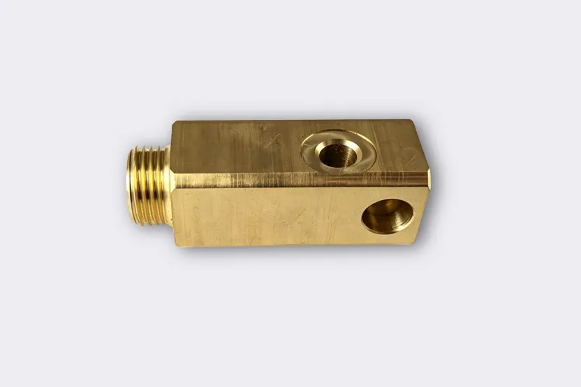 CNC machined brass manifold block with threaded ports.