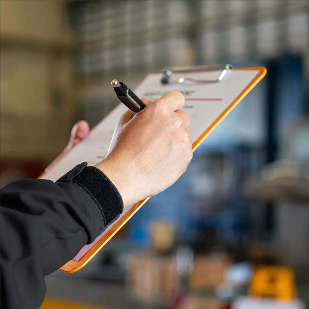Inspector recording results on a clipboard on the shop floor.