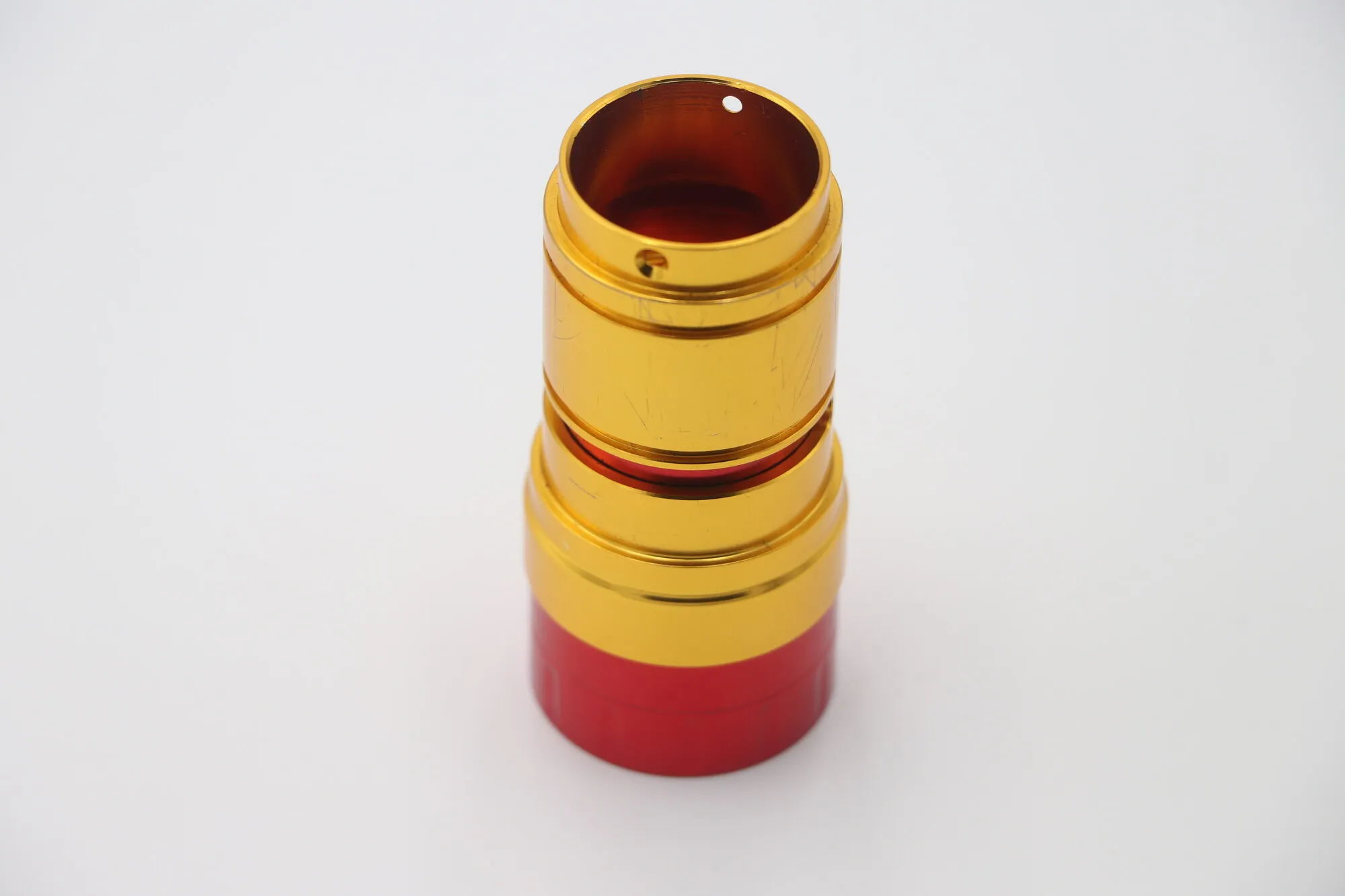 Close detail of a gold and red anodized CNC turned aluminum sleeve