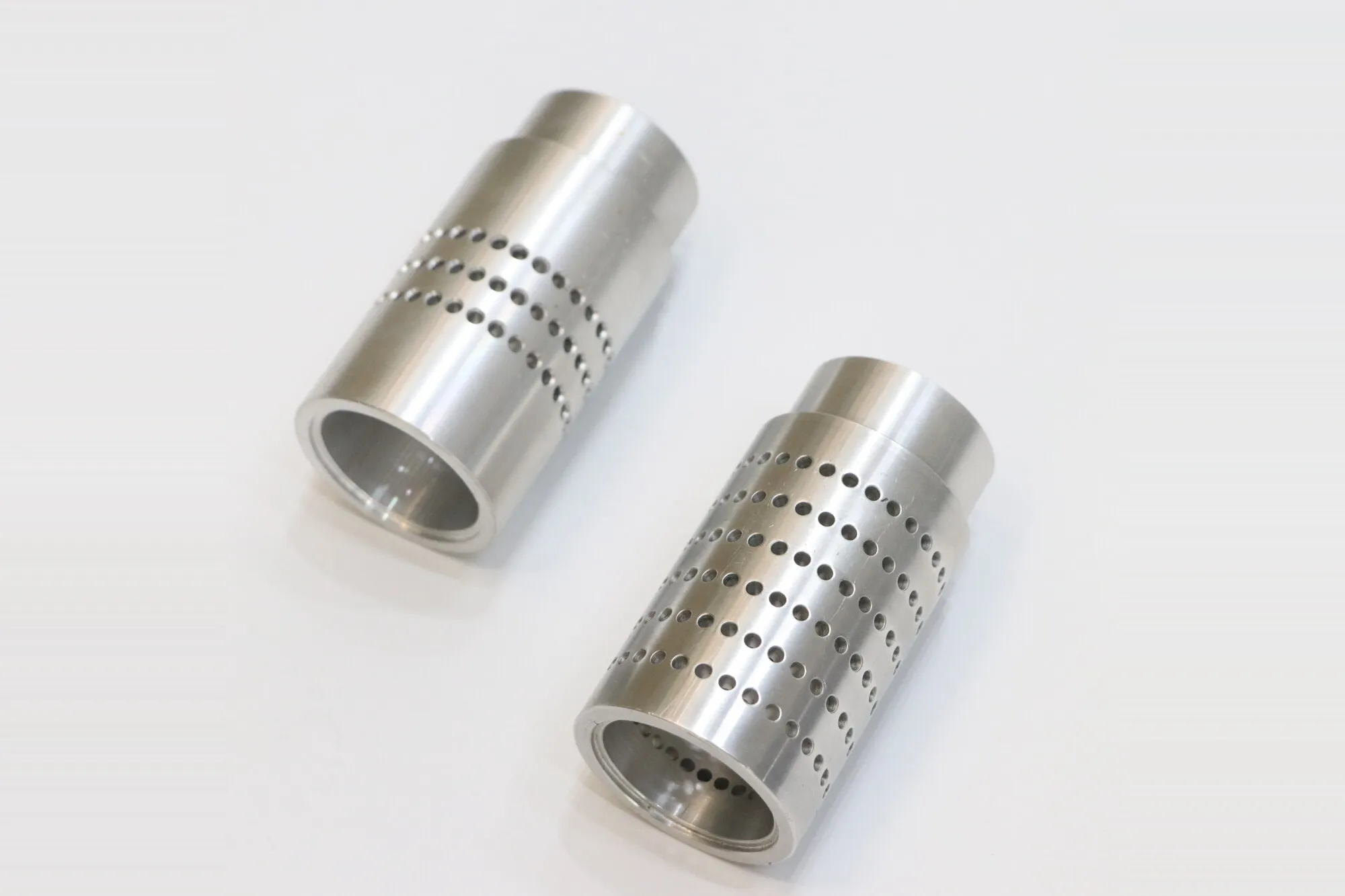 CNC turned stainless steel sleeves with rows of cross-drilled perforations