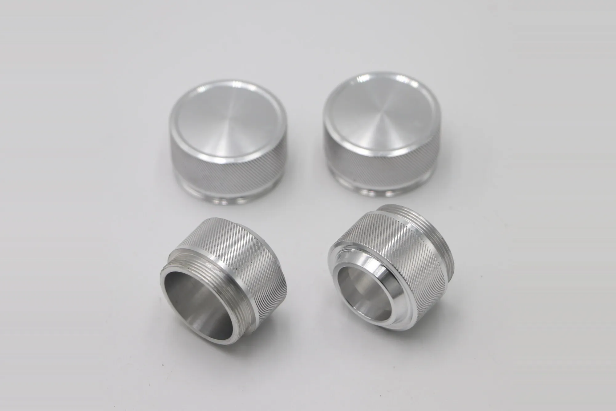 Four CNC turned aluminum knobs with diamond knurled grips and threaded bores