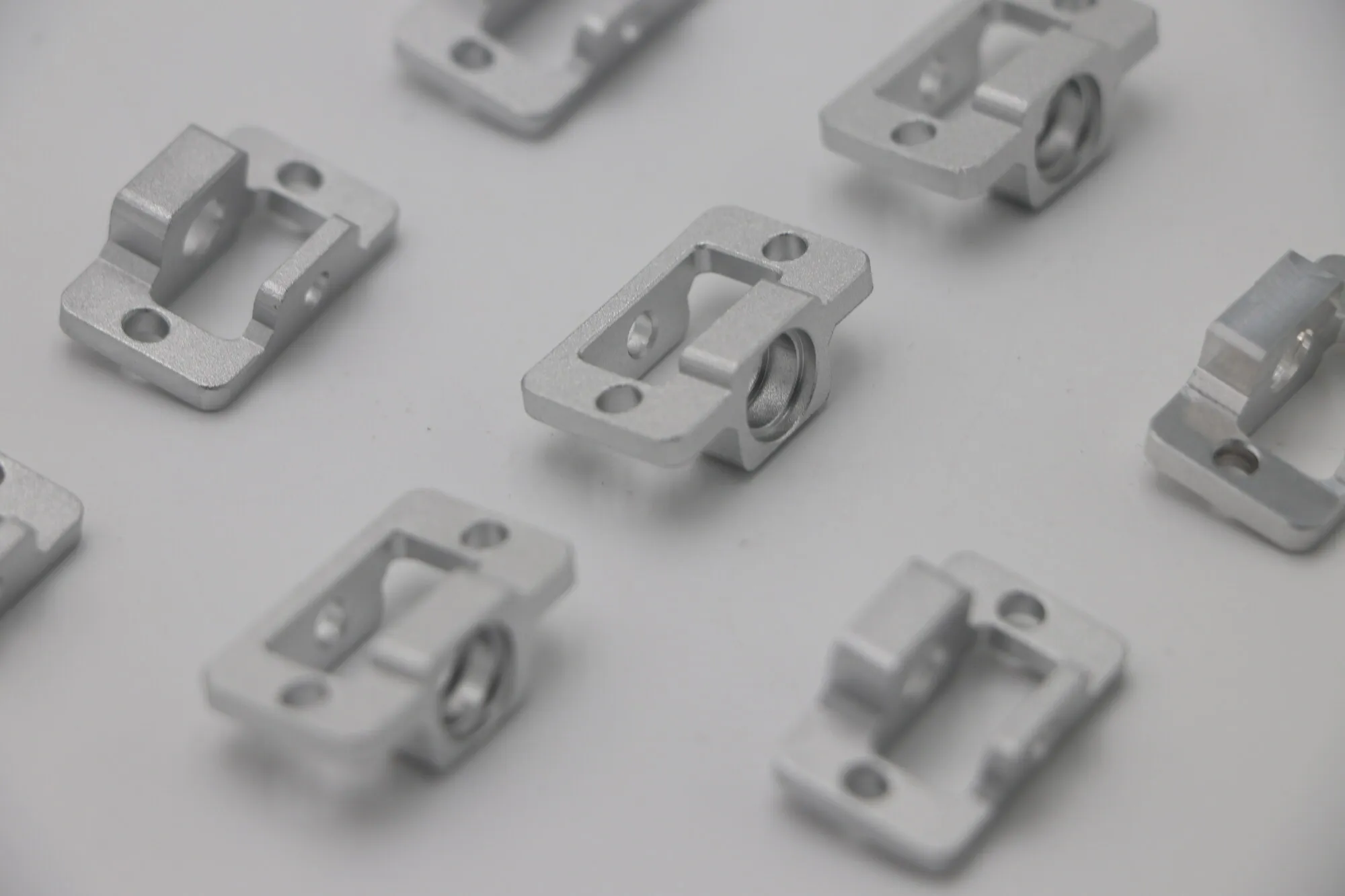 Batch of eight identical bead-blasted machined aluminum clamp blocks