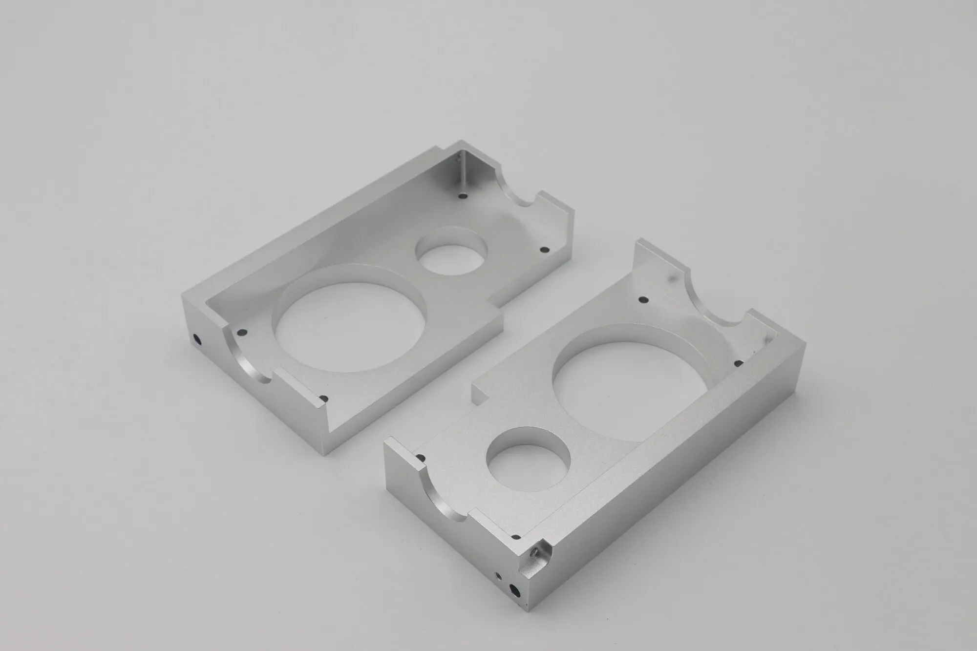Pair of machined aluminum enclosure halves with bored apertures and sealing faces