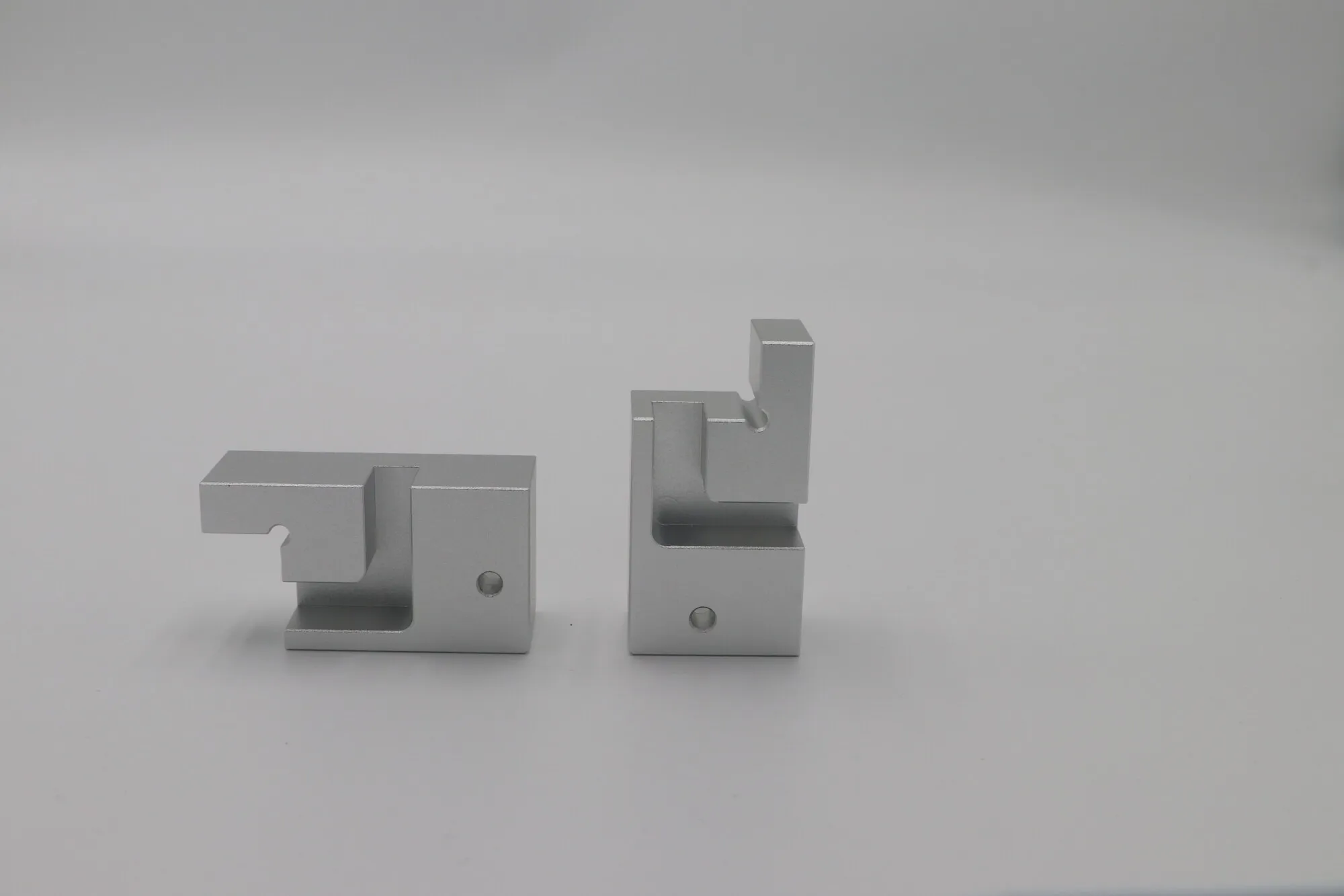 Pair of CNC milled aluminum brackets with slotted and stepped features
