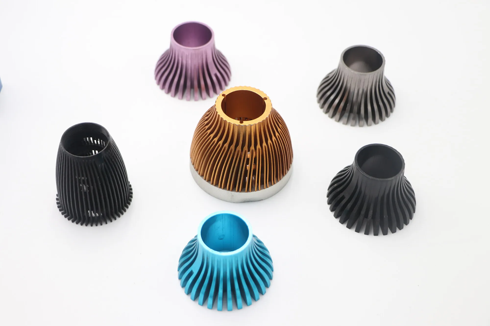 Group of radial-fin machined aluminum LED lamp heat sinks in black, purple, copper and cyan anodized finishes