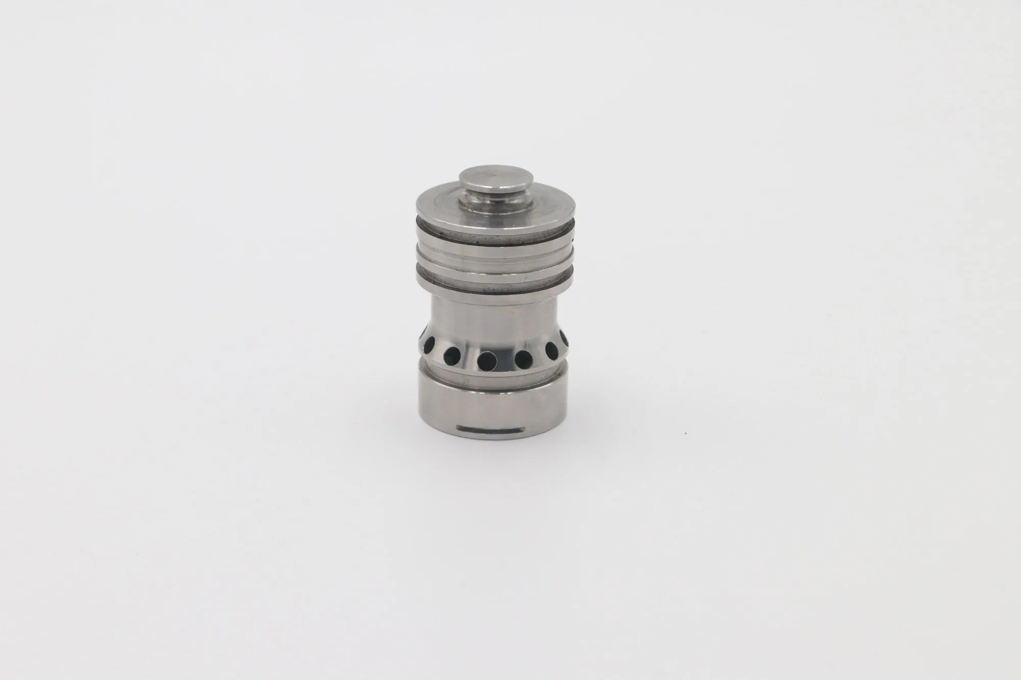 Close detail of a machined stainless steel valve cartridge with turned lands and cross-drilled ports